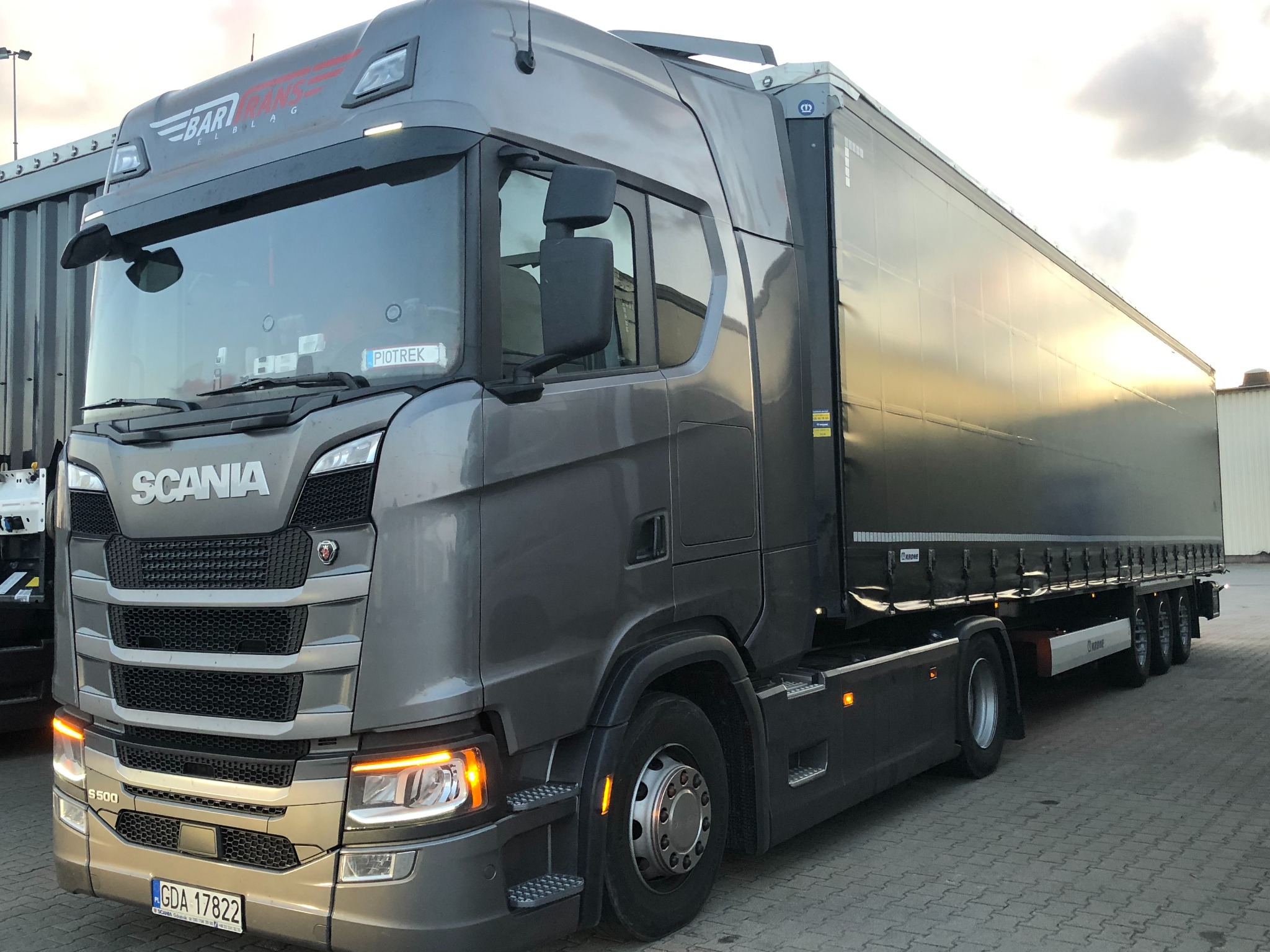 Szary ciągnik siodłowy Scania S500 z naczepą, tablica rejestracyjna GDA 17822, na szybie naklejka z imieniem 'Piotrek', logo Bari Trans Eiblag na kabinie.