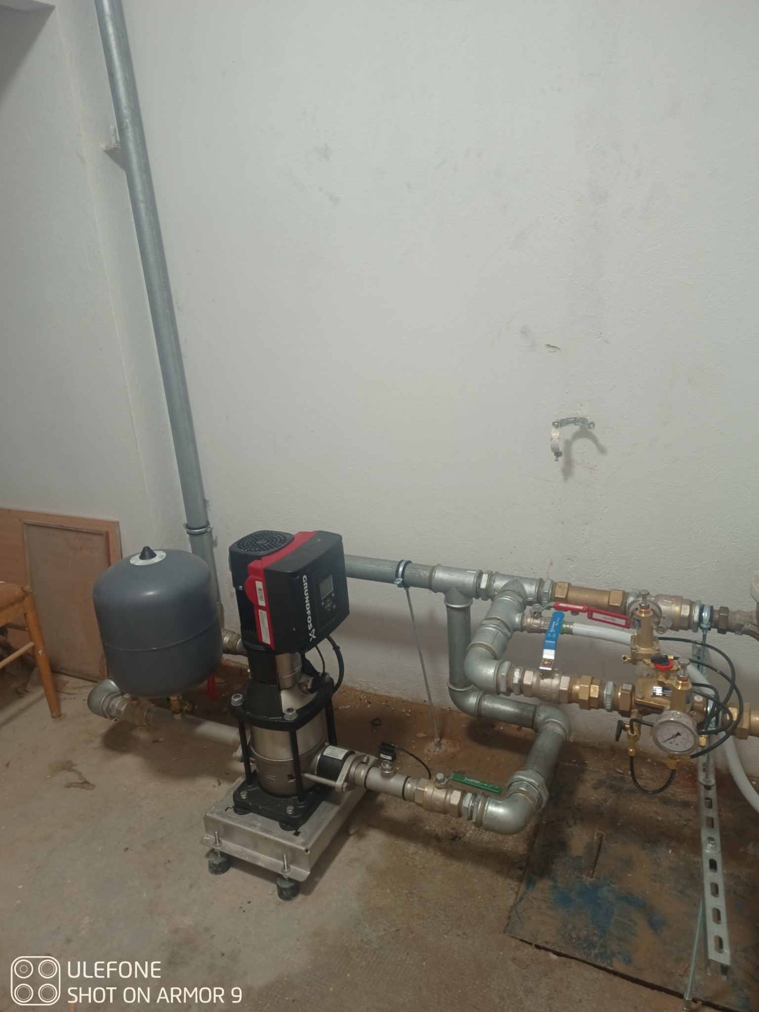 Zestaw hydroforowy Grundfos X zamontowany w pomieszczeniu technicznym, widoczne rury i manometr, surowy stan wykończenia ścian i podłogi.