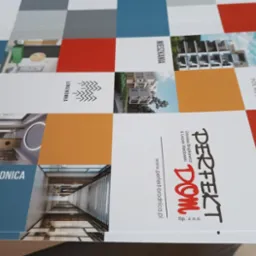 Arkusz z nadrukowanymi projektami graficznymi nieruchomości, w tym wizualizacje osiedli i mieszkań, opakowany w folię bąbelkową.