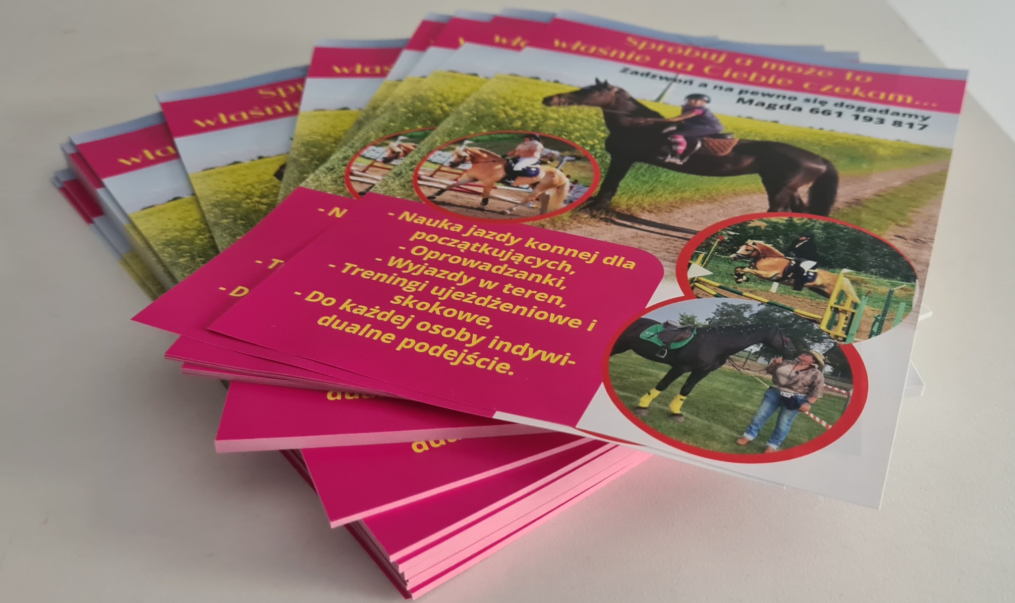 Stos różowych ulotek reklamujących naukę jazdy konnej, z fotografiami koni i jeźdźców w różnych sytuacjach, w tym skoki przez przeszkody i jazda po łące.