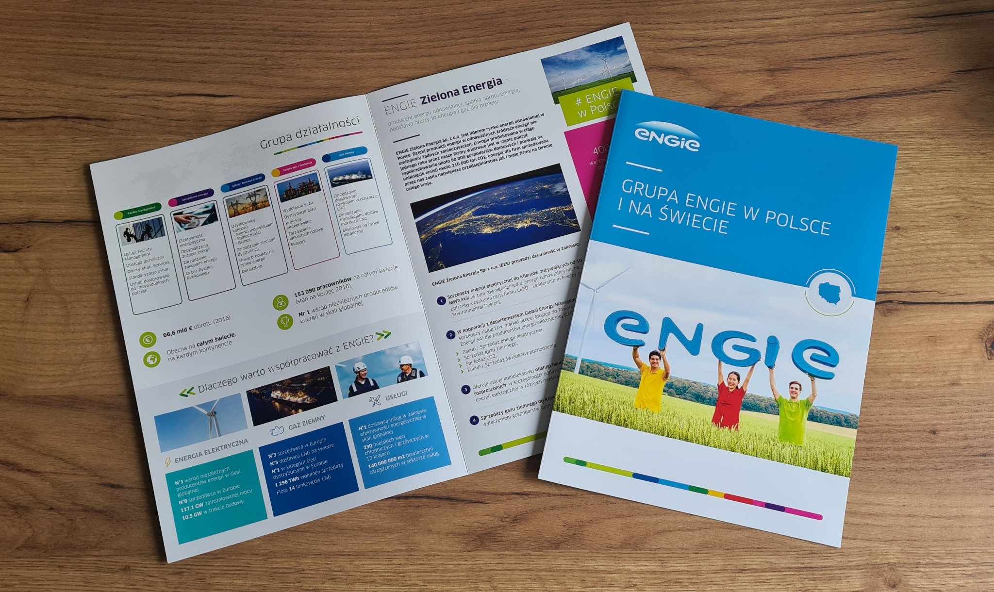 Rozłożona broszura i ulotka firmy Engie prezentujące profil działalności, z naciskiem na zieloną energię, z elementami graficznymi, danymi liczbowymi i zdjęciem uśmiechniętych osób trzymających...