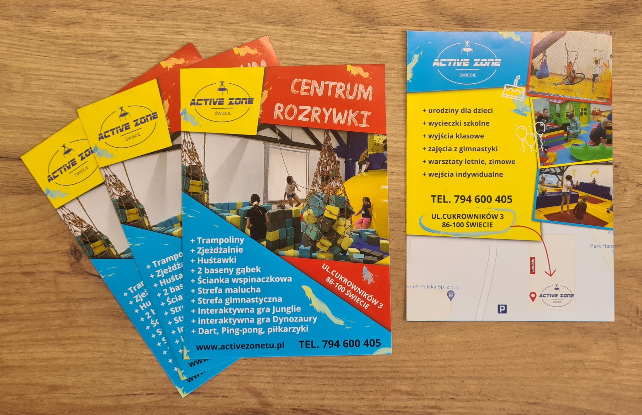 Stos ulotek i wizytówek z ofertą Centrum Rozrywki Active Zone w Świeciu, prezentujące atrakcje dla dzieci, w tym trampoliny, zjeżdżalnie i ściankę wspinaczkową, oraz dane kontaktowe i mapę dojazdu.