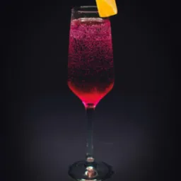 Kieliszek do szampana wypełniony różowym, musującym napojem, ozdobiony skórką pomarańczy na ciemnym tle.