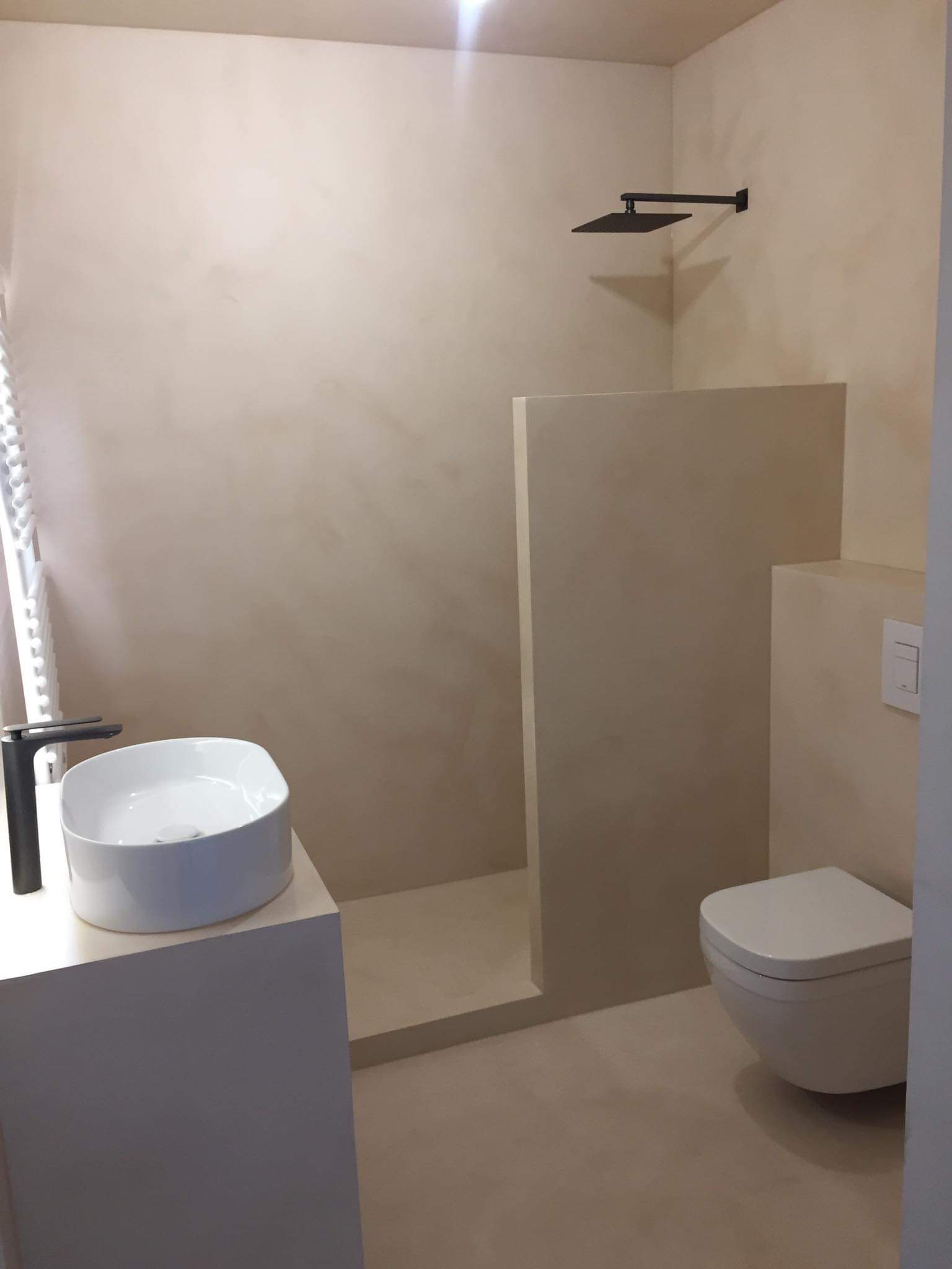 Minimalistyczna łazienka w odcieniach beżu z kabiną typu walk-in, armaturą w kolorze czarnym i umywalką nablatową.