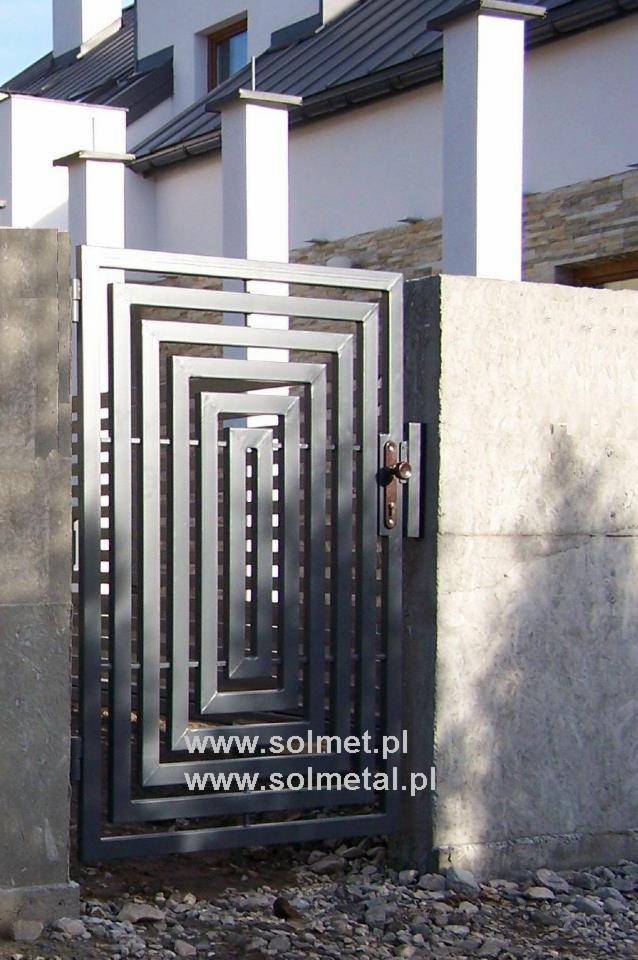 Nowoczesna brama wjazdowa metalowa z geometrycznym wzorem kwadratów, zamontowana między betonowymi słupkami, na tle białego domu.