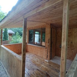 Taras Prytula.UA🇺🇦 - Drewniana altana z balustradą i oknami, widok z zewnątrz, widoczne ślady impregnacji drewna i wałek do malowania na podłodze.