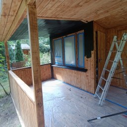 Taras Prytula.UA🇺🇦 - Malowanie drewnianej altany na działce w Warszawie: widoczna drabina, farba, zaklejone okna i pomalowana na czarno górna część ściany.