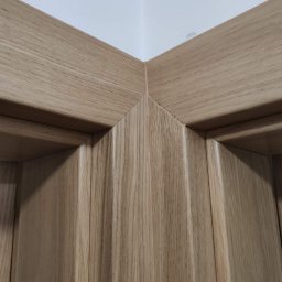 Doorway Krystian Stępień - Detal narożnika ościeżnicy z jasnego drewna, widoczne precyzyjne łączenie elementów i struktura drewna.