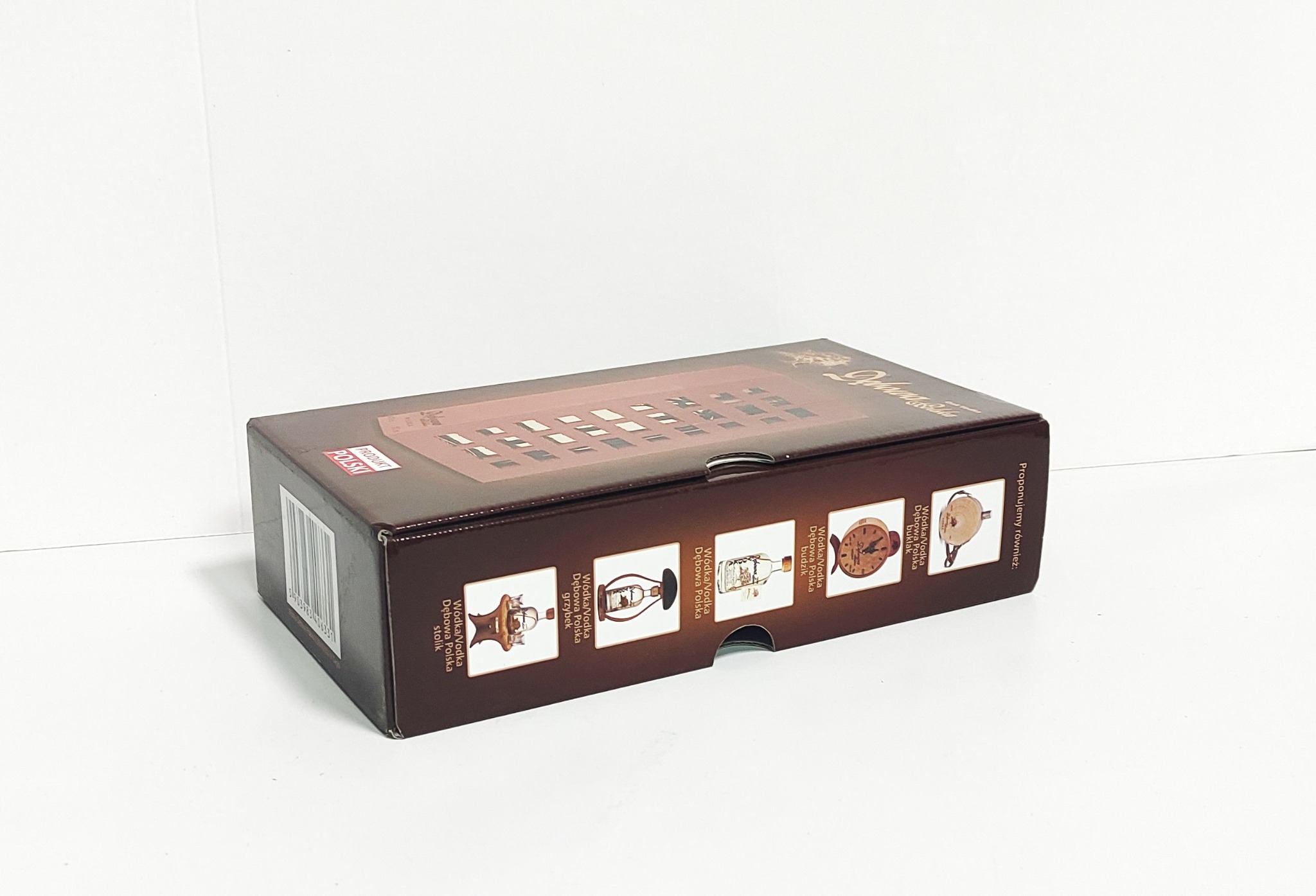 Brązowe kartonowe pudełko z nadrukowanymi grafikami różnych modeli wódek Dębowa Polska, ustawione na białym tle.