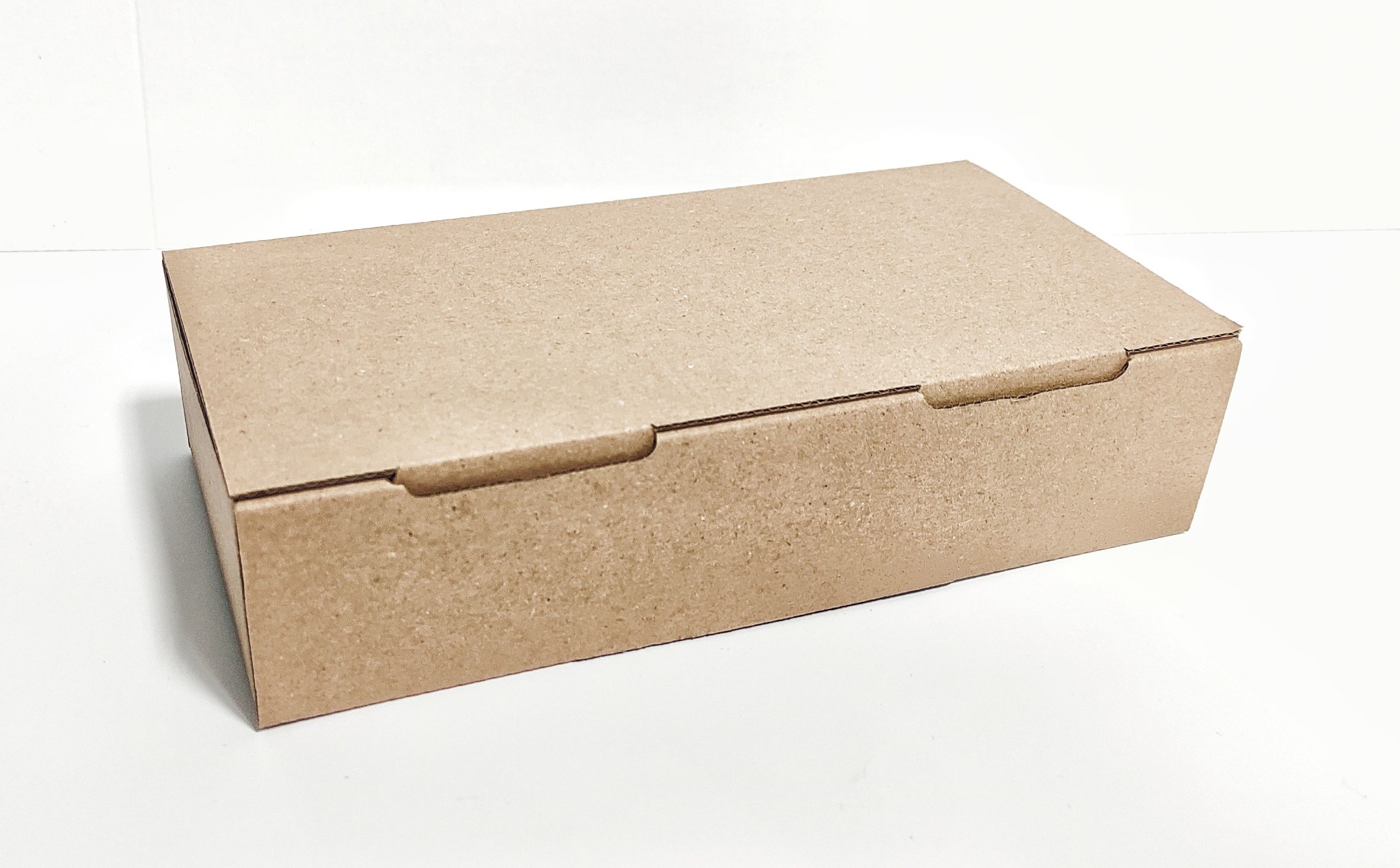 Zamknięte, prostokątne pudełko z brązowej tektury, widoczne na białym tle, z delikatnym cieniem po prawej stronie.
