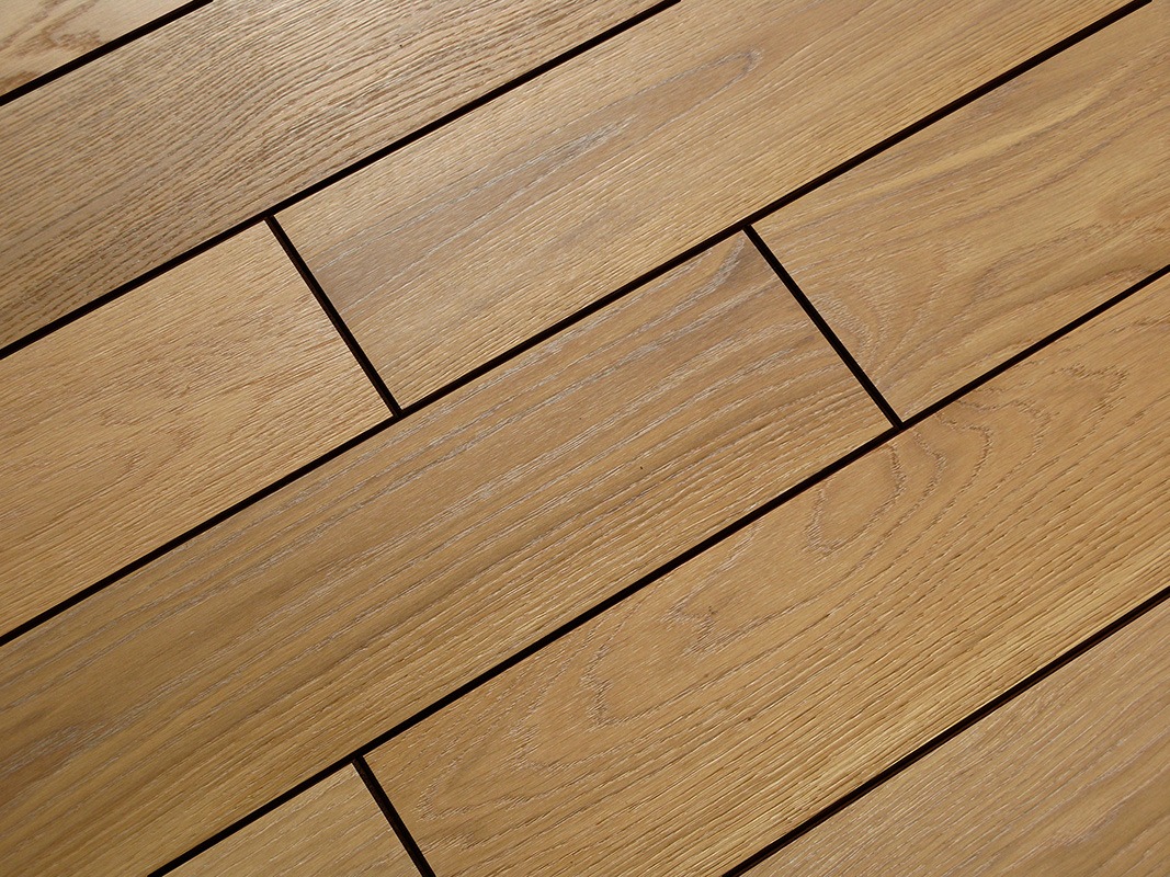 Jasne, dębowe deski ułożone diagonalnie, z widoczną strukturą drewna i ciemnymi fugami, oświetlone naturalnym światłem.
