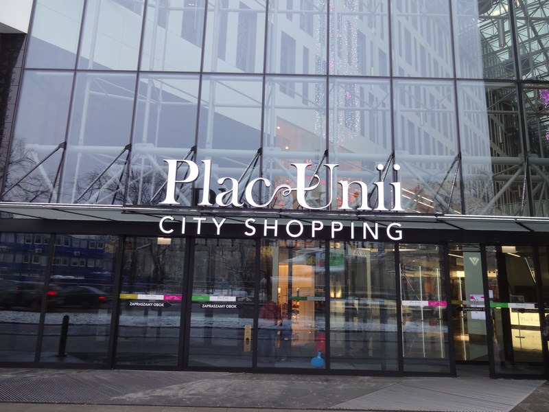 Elewacja budynku centrum handlowego Plac Unii City Shopping z dużymi szklanymi panelami i białym napisem nazwy nad wejściem.