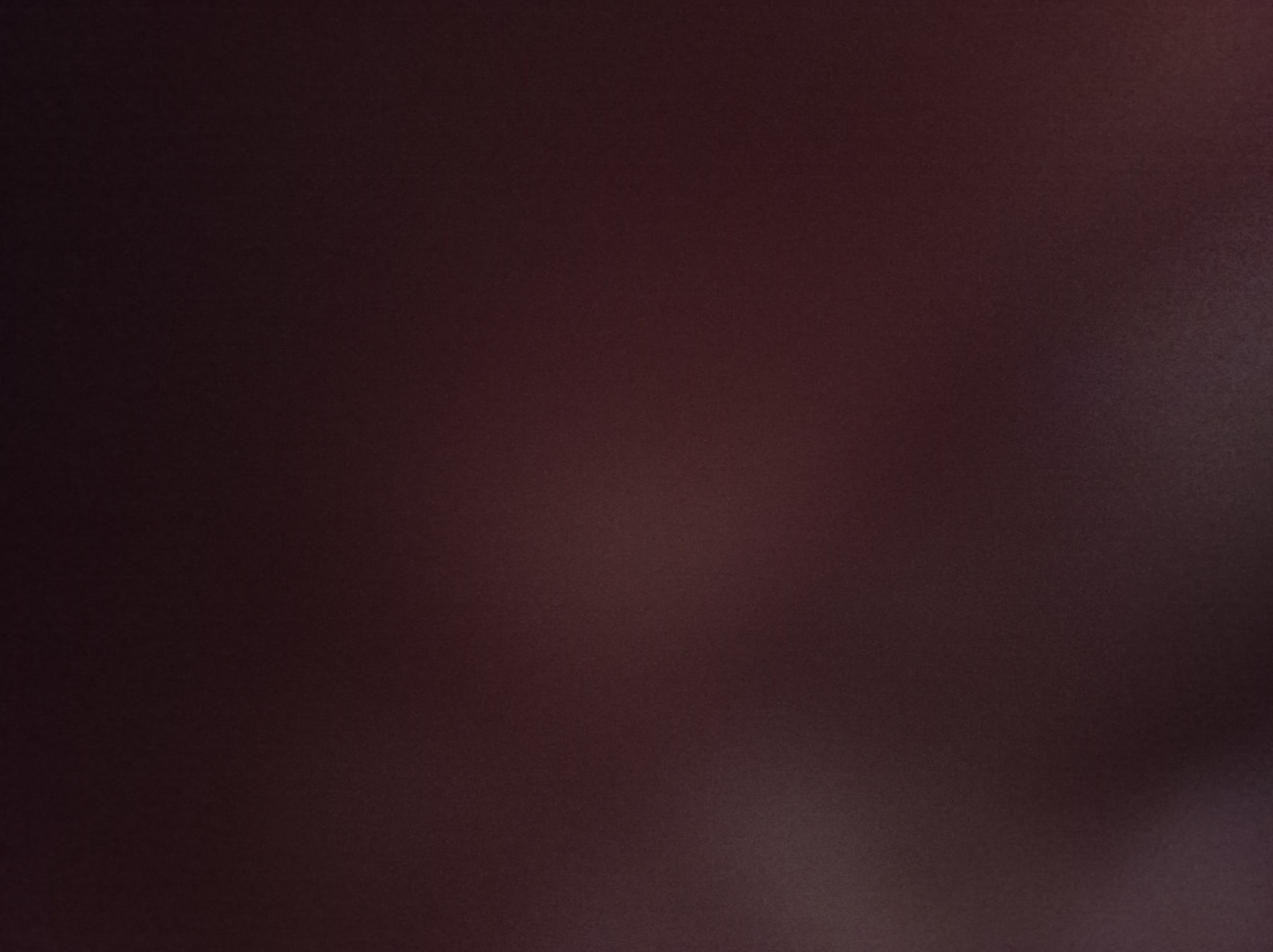 Rozmazane, ciemnobrązowe tło, prawdopodobnie fragment zdjęcia z Międzychodu, zbyt ciemne, aby określić szczegóły.