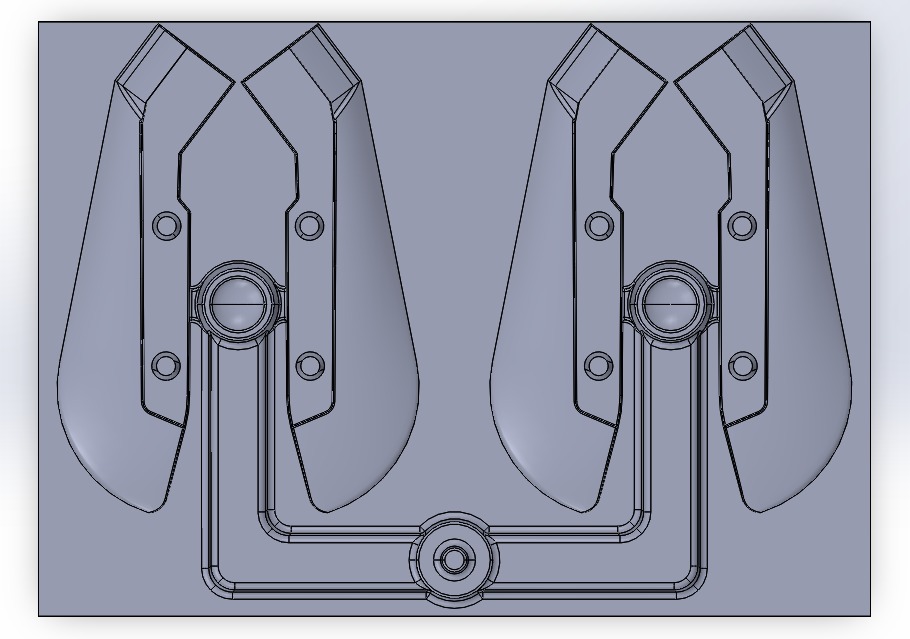 CAD model showing a symmetrical mold design with two cavities, a central sprue, and runner system, rendered in a neutral gray color scheme.