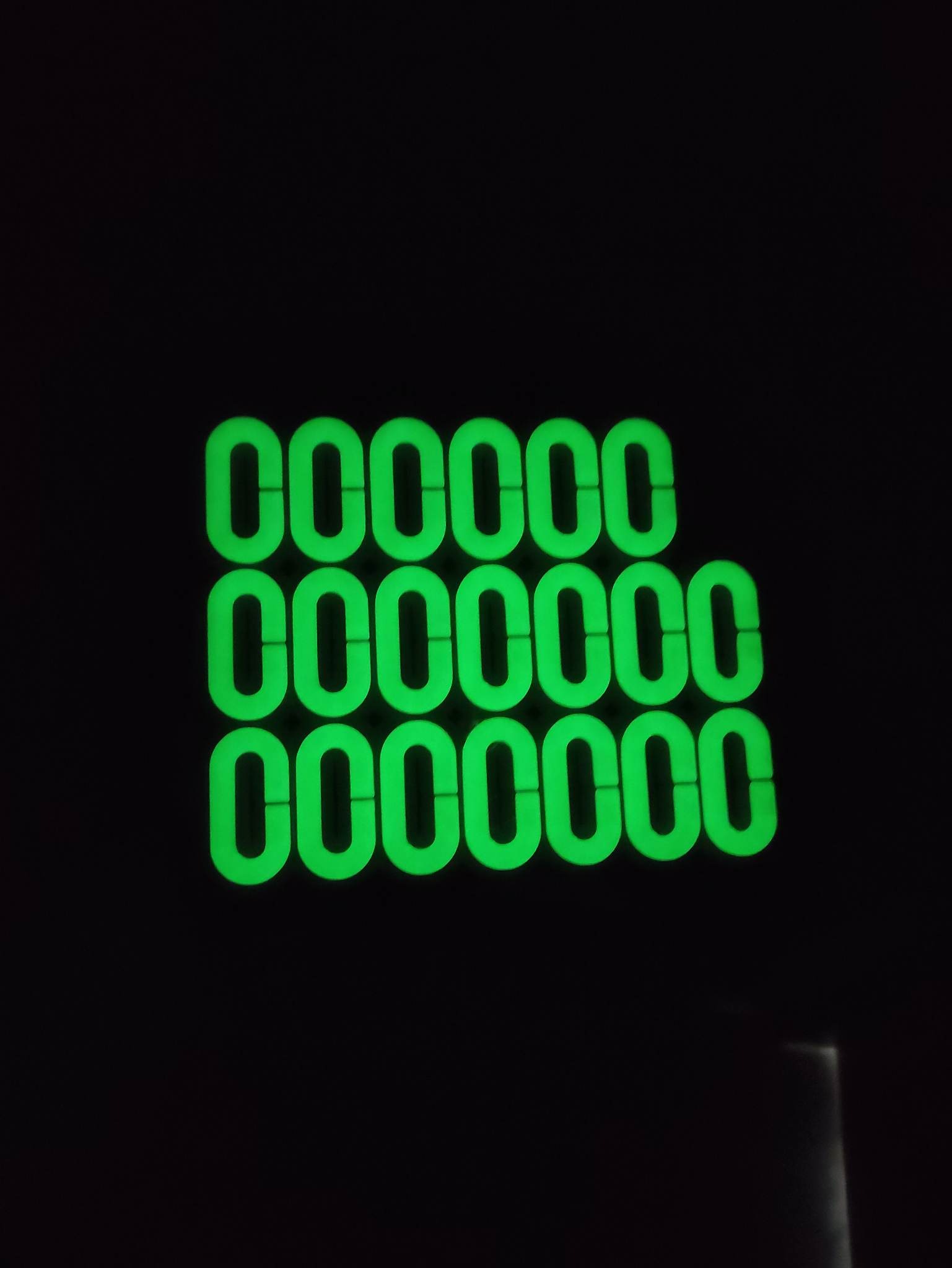 Świecące na zielono cyfry '0' ułożone w trzech rzędach na ciemnym tle, tworzące abstrakcyjny wzór.