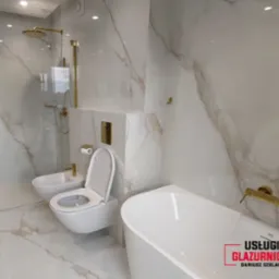 Elegancka łazienka z płytkami imitującymi marmur, złotą armaturą i kabiną prysznicową typu walk-in oraz wiszącą toaletą i bidetem.