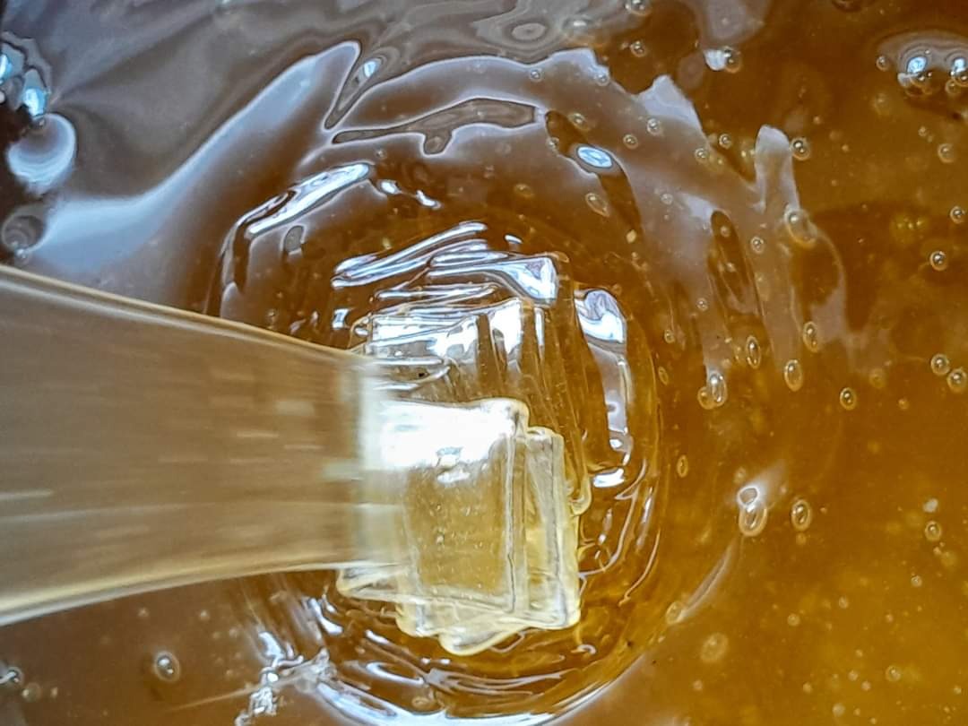 Gęsta, bursztynowa ciecz z pęcherzykami powietrza, mieszana przezroczystym mieszadłem.