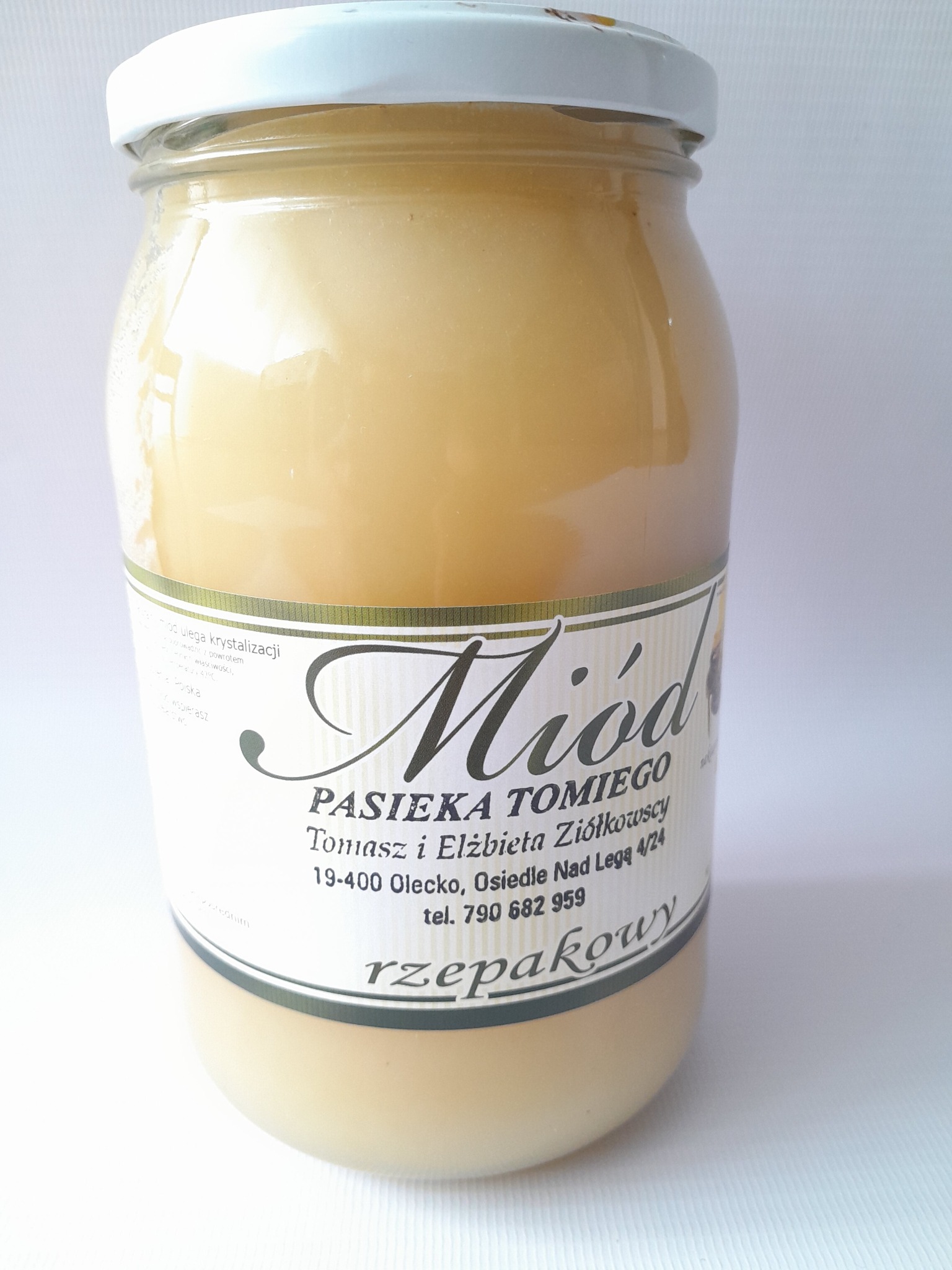 Słoik rzepakowego nektaru z Pasieki Tomiego, z białą nakrętką i etykietą z informacjami o producencie, na jasnym tle.