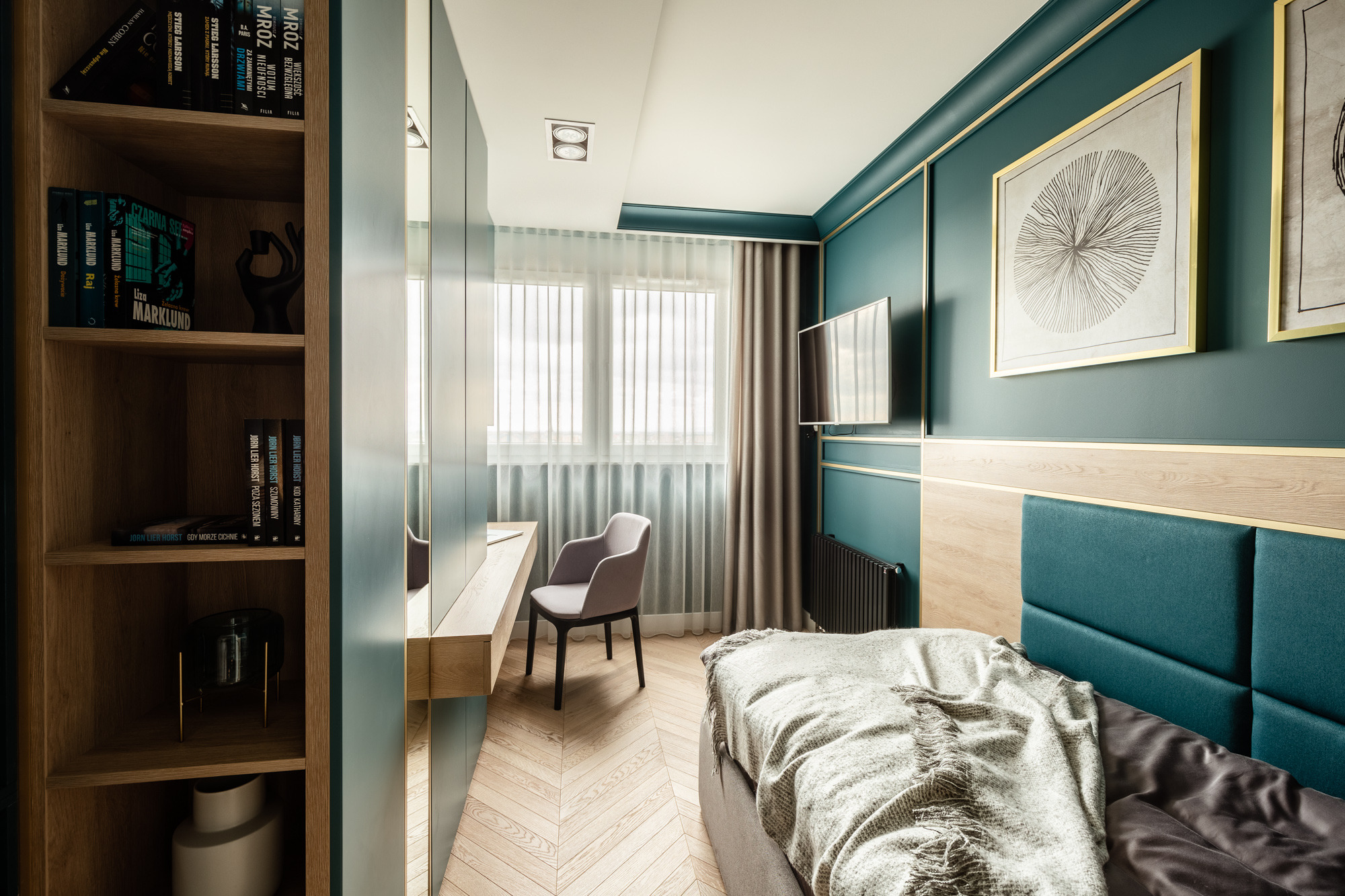 Komfortowa sypialnia z miejscem do pracy: zielone ściany z listwami, łóżko z turkusowym zagłówkiem, biurko z szarą krzesłem i regał z książkami.