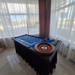 Party Dealer - Stół do ruletki z żetonami i napisem 'Party Dealer' w Katowicach, ustawiony w jasnym pomieszczeniu z oknami i zasłonami, gotowy do imprezy tematycznej.