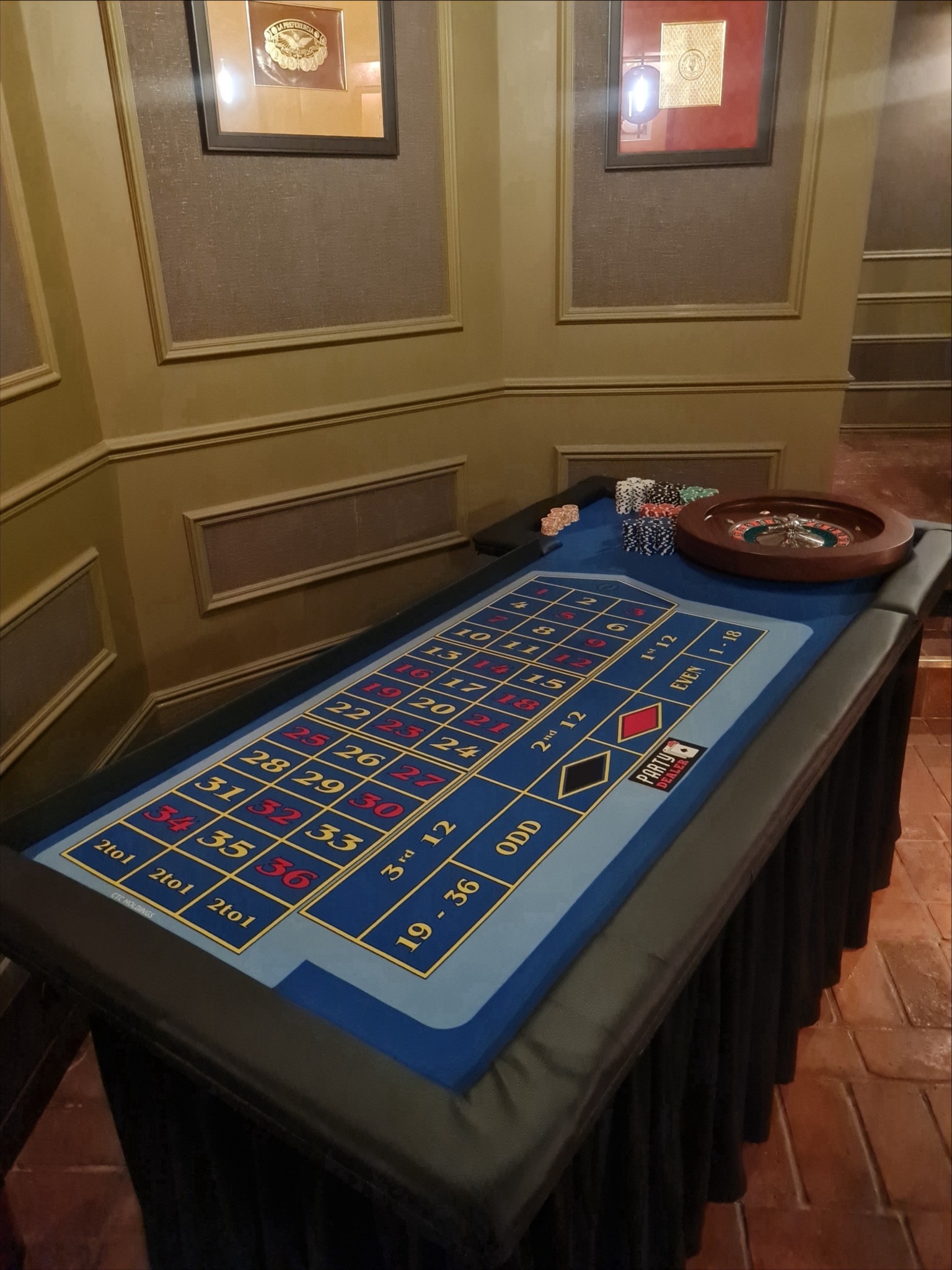 Stół do ruletki z żetonami i kołem, przygotowany do gry. Widoczne numery i oznaczenia na stole, eleganckie otoczenie. Idealny na imprezę tematyczną.