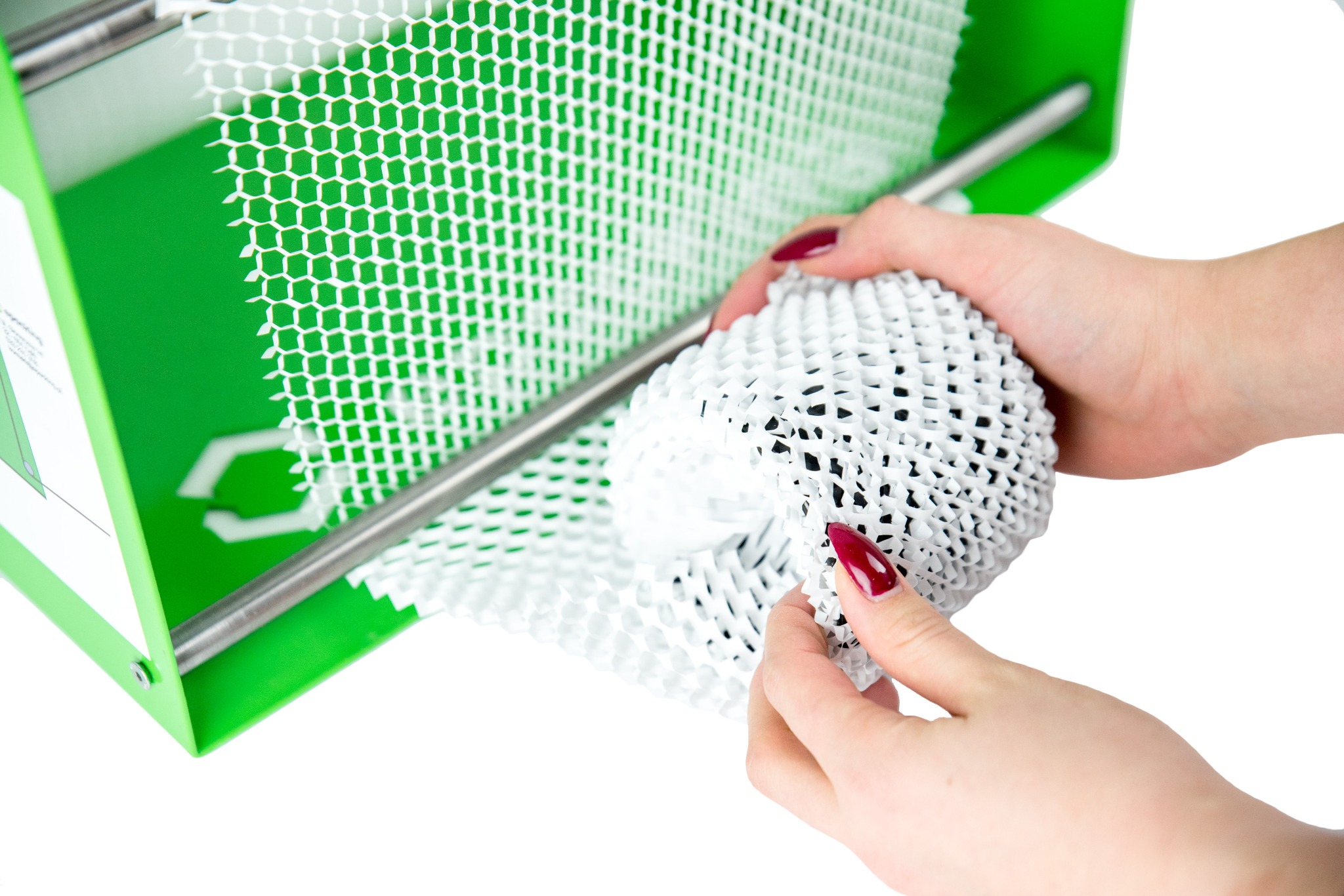 Aplikacja białej, perforowanej siatki opakowaniowej na kulisty przedmiot przy użyciu zielonego aplikatora z metalowym prętem.