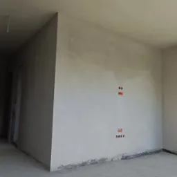 Wnętrze po szpachlowaniu z widocznymi puszkami elektrycznymi, gładzią na ścianach i oknem z widokiem na góry. Podłoga surowa, wylewka.