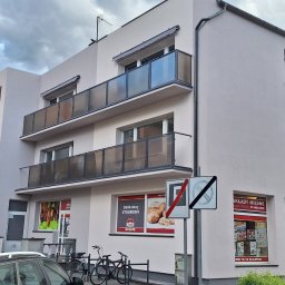 Firma Remontowo-Budowlana Jacoob Jakub Jankowski - Elewacja budynku po remoncie z balkonami i oknami. Jasna kolorystyka, widoczne detale wykończenia. Ujęcie z poziomu ulicy, z elementami otoczenia miejskiego.