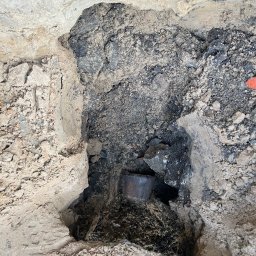 hidroallpl - Wykop w ziemi z widoczną rurą kanalizacyjną, otoczony gruzem i ziemią.