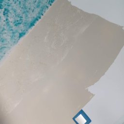 Jakub Wawrzyniak - Fragment sufitu w trakcie prac wykończeniowych, z widocznymi śladami szpachlowania i malowania, częściowo pokryty turkusową farbą dekoracyjną, zabezpieczony otwór taśmą malarską.