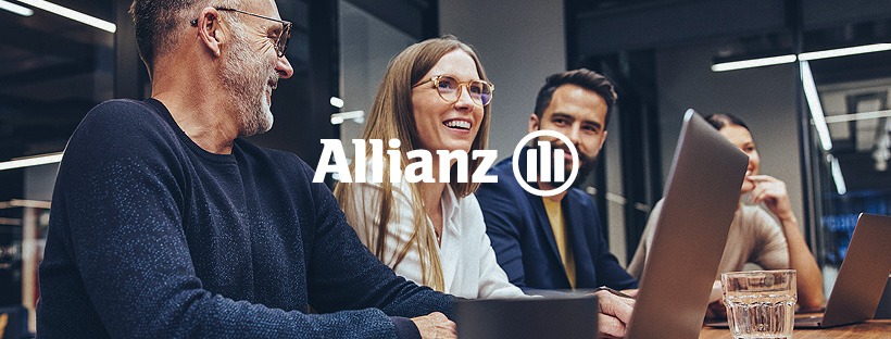 Grupa uśmiechniętych osób siedzi przy stole z laptopami, z logo Allianz w tle, sugerując spotkanie biznesowe związane z ubezpieczeniami.