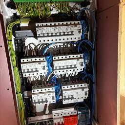 Wentplast - Rozdzielnica elektryczna w białej obudowie z widocznymi bezpiecznikami, przewodami w różnych kolorach i listwami zaciskowymi. Instalacja w nowym budynku.