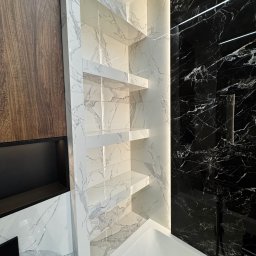 Yurii Yatsyshyn Yat-Fliz - Nowoczesna łazienka z czarno-białymi marmurowymi płytkami, podświetlane półki z białego marmuru, drewniana okładzina i biała wanna.