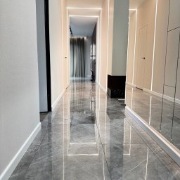 Yurii Yatsyshyn Yat-Fliz - Długi korytarz z szarymi marmurowymi płytkami podłogowymi, oświetleniem LED wzdłuż ścian i sufitu, oraz lustrem na ścianie po prawej stronie.