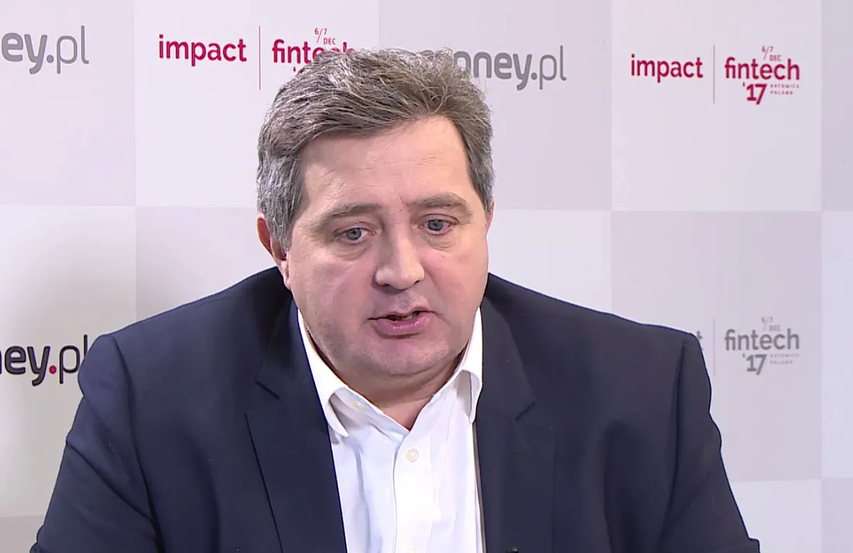 Mężczyzna w garniturze przemawia na tle logotypów konferencji finansowej Fintech '17 oraz money.pl.