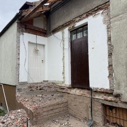 Rem-Ekspert Oleh Yefremov - Częściowo rozebrany budynek z odsłoniętą konstrukcją dachu, gruzem na schodach i łopatą opartą o ścianę. Widoczne ślady po wyburzeniach.