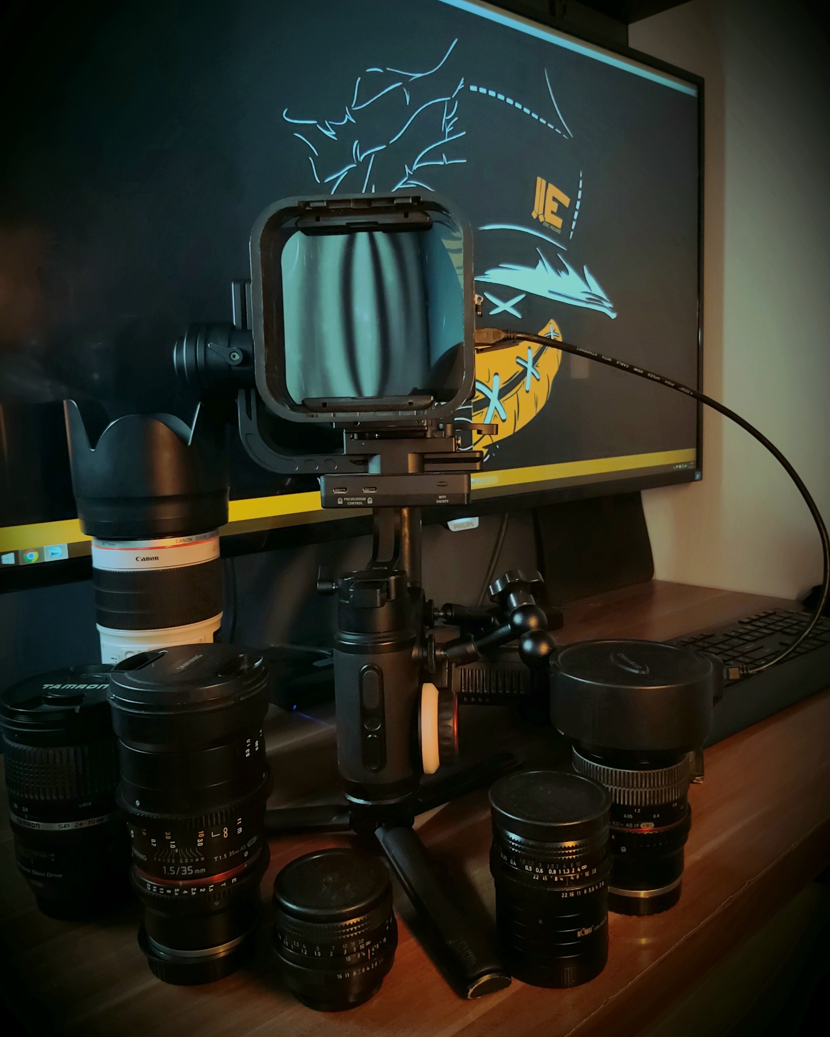 Zestaw obiektywów, stabilizator kamery i monitor z grafiką w stylu graffiti na biurku filmowca.