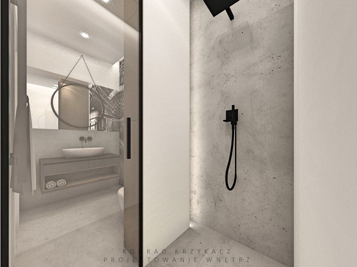 Nowoczesna łazienka z kabiną prysznicową typu walk-in, betonową ścianą pod prysznicem z czarną armaturą i umywalką nablatową z okrągłym lustrem w tle.