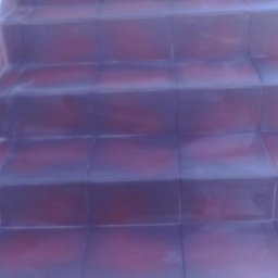 Usługi ogólnobudowlane - Wykończone schody z bordowo-szarych płytek ceramicznych, widoczne z dołu pod lekkim kątem. Minimalistyczny design, gładka powierzchnia, fuga w odcieniu płytek.