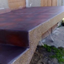 Usługi ogólnobudowlane - Wykończone płytkami schody wejściowe do budynku w Dubinach. Płytki w odcieniach brązu i beżu, z widoczną strukturą kamienia. Wykończenie z efektem 'kamyczków'.