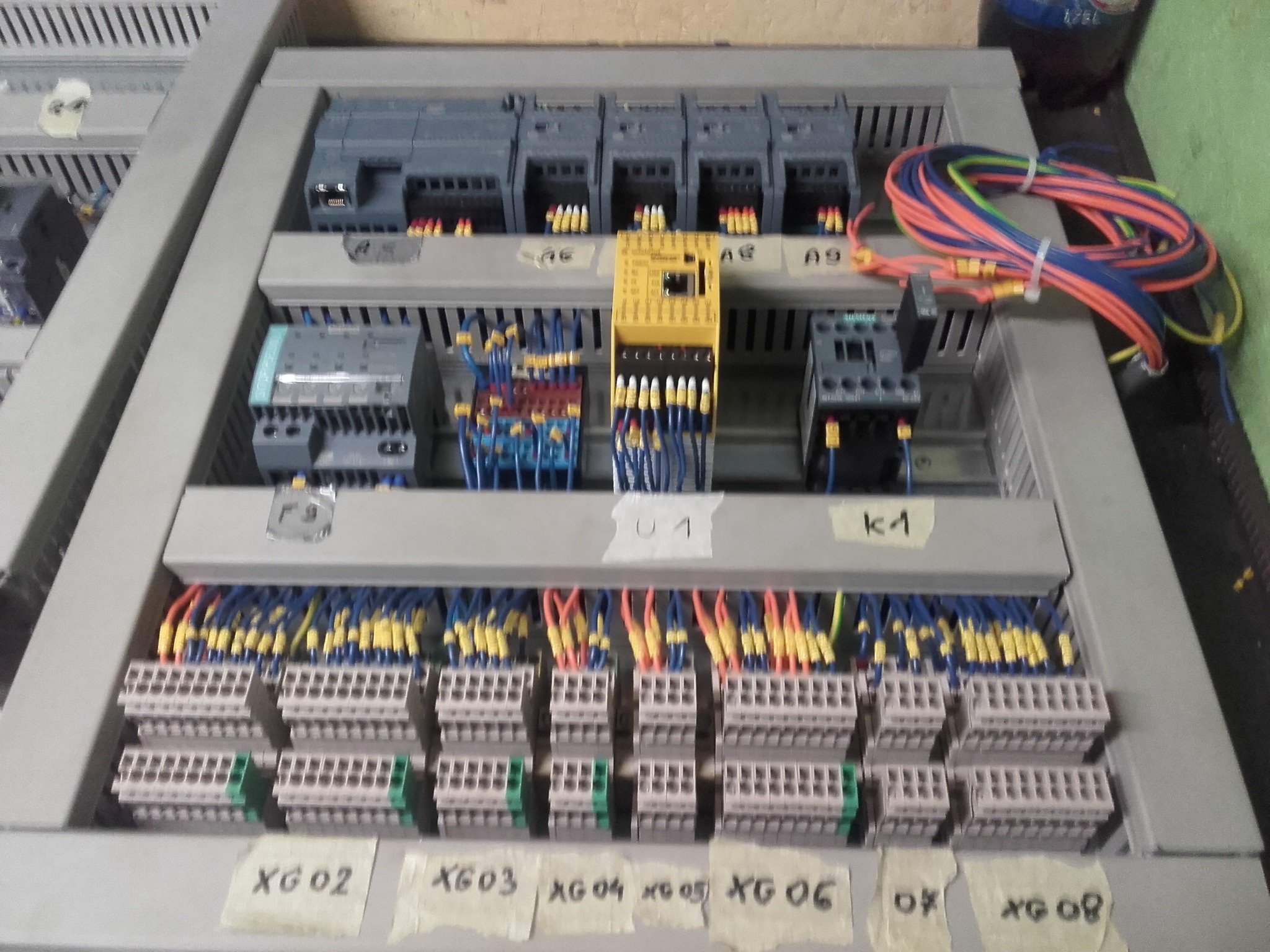 Rozdzielnica elektryczna z modułami, przewodami i złączkami, oznaczona etykietami XG02-XG08, A6-A9, K1 i U1, zainstalowana w Kątach Wrocławskich.