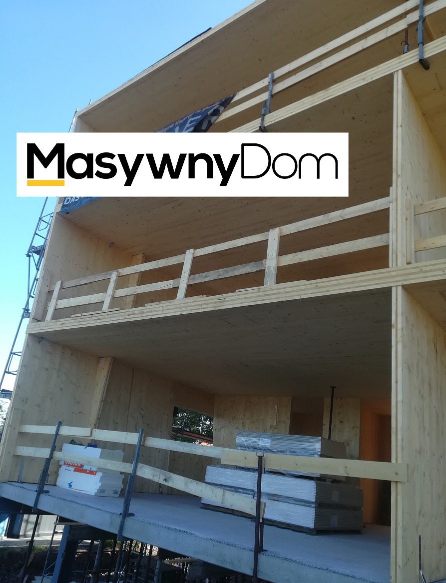 Wznoszona konstrukcja drewniana dwukondygnacyjnego budynku z widocznymi elementami szkieletu i materiałami budowlanymi na betonowej płycie fundamentowej, z logo firmy nałożonym na zdjęcie.