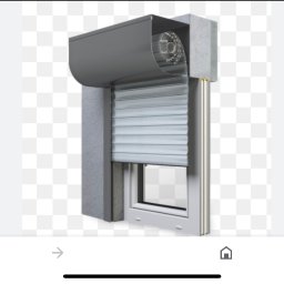 Majgo Łukasz Rudzki - Szary system rolet zewnętrznych z widocznym mechanizmem zwijającym, zamontowany na oknie w ścianie z szorstkiego betonu.