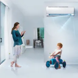 Wnętrze jasnego salonu z białą klimatyzacją ścienną, kobieta obsługuje urządzenie mobilne, a dziecko bawi się na niebieskim autku, wizualizacja działania systemu chłodzenia.