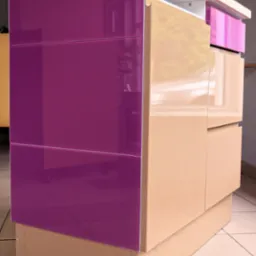 Komoda z frontami w kolorze fuksji i beżowym korpusem, widoczne trzy szuflady, blat w kolorze jasnego drewna, ustawiona na kafelkach.