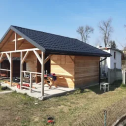 Montaż dachu z blachy na drewnianej konstrukcji w Radomsku, widoczne narzędzia i materiały budowlane, budynek w trakcie budowy.