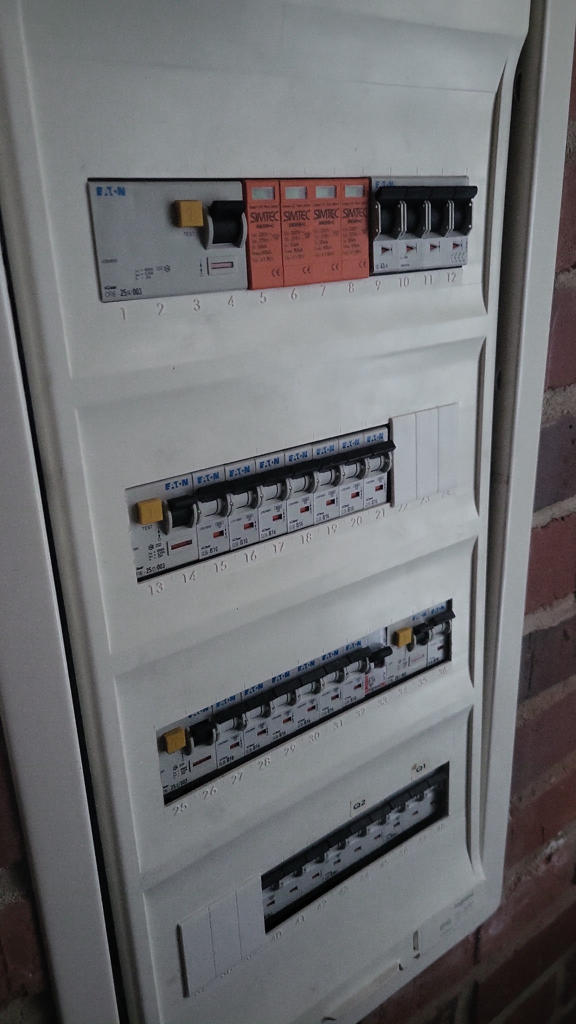 Rozdzielnica elektryczna firmy Eaton z bezpiecznikami SIMTEC zamontowana na ścianie z czerwonej cegły, widok z bliska.