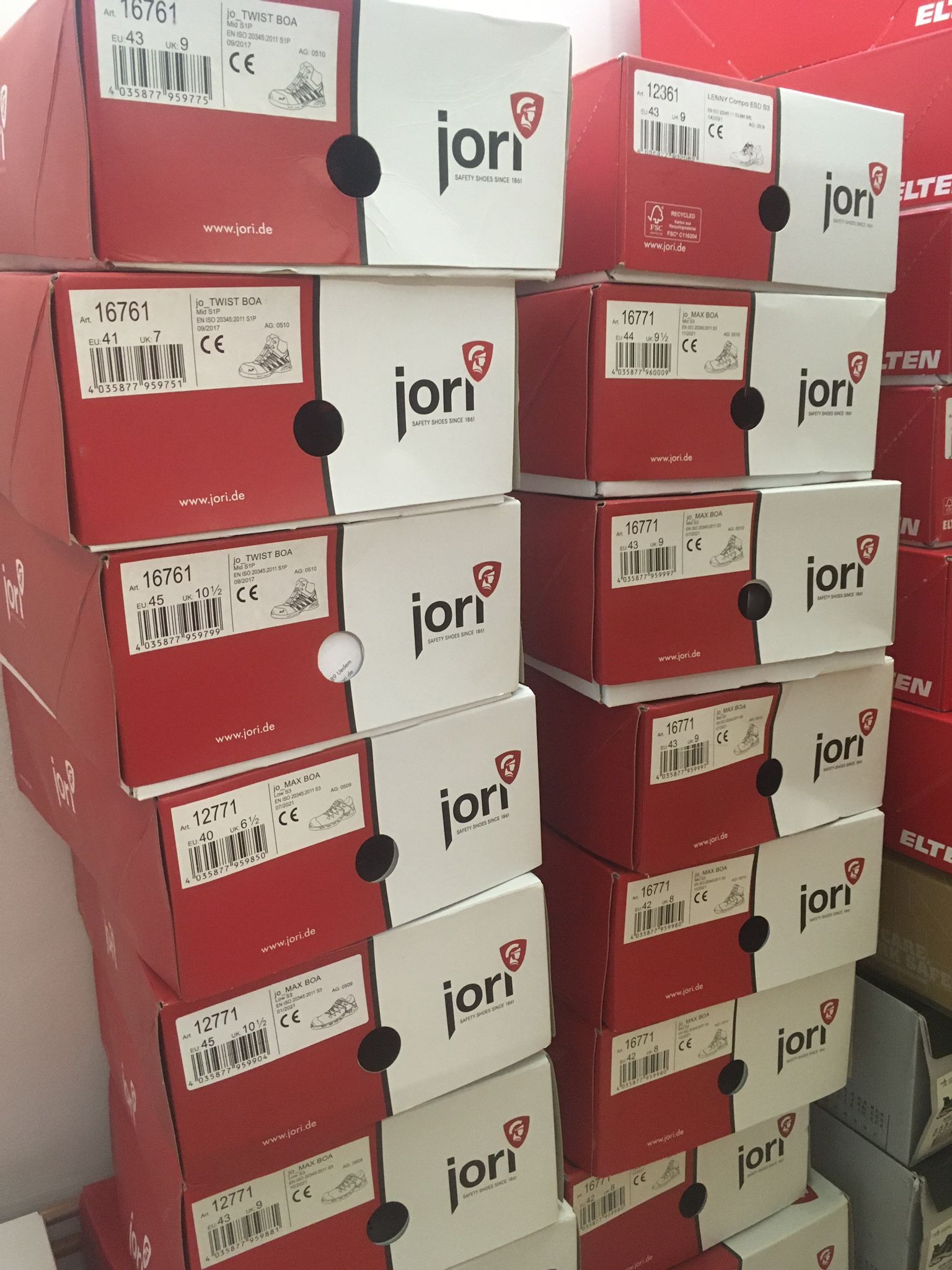 Stos pudełek z obuwiem roboczym marki Jori, ukazujących różne modele i rozmiary, z widocznymi etykietami informacyjnymi i logo producenta.
