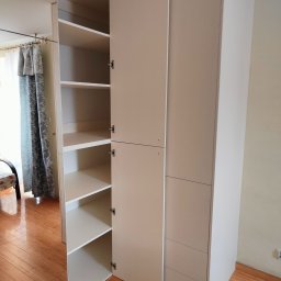 HOHO PROJEKT Adam Śleszyński - Jasna szafa wnękowa z otwartymi drzwiami, ukazująca półki. Widoczne detale wykończenia i dopasowanie do wnętrza. Na podłodze parkiet.