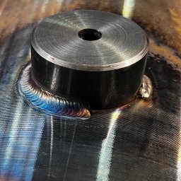 Wojciech Czerenda - Metalowa rura z przyspawanym elementem, widoczne ślady po spawaniu z charakterystycznymi kolorami.